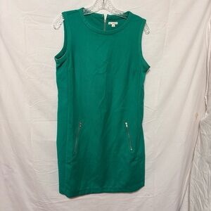 Green sleeveless shift dress with a round neckline and two front zip pockets.